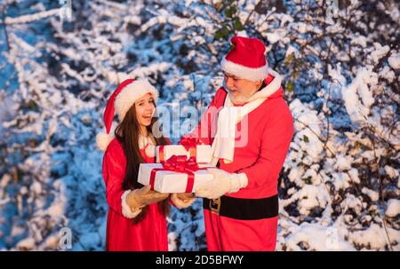 Le matin de noël gelé. Père Noël et petite-fille. Il est temps de faire des miracles. Généreux Père Noël. Enfant bonne fille plein air neige nature. joyeux noël. Concept d'enfance heureuse. Cadeaux du Père Noël. Banque D'Images