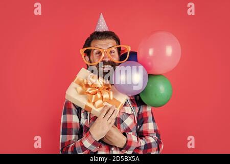 S'amuser. Drôle d'homme dans son chapeau d'anniversaire. Joyeux Noël. Fête à la folie. Amusez-vous avec des ballons. Préparez-vous pour l'anniversaire. Gestionnaire d'événements avec boîte cadeau. Homme brutal à la fête. Banque D'Images