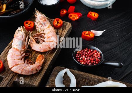 crevettes géantes aux fruits de mer sur une planche en bois avec épices sur fond noir table en bois Banque D'Images