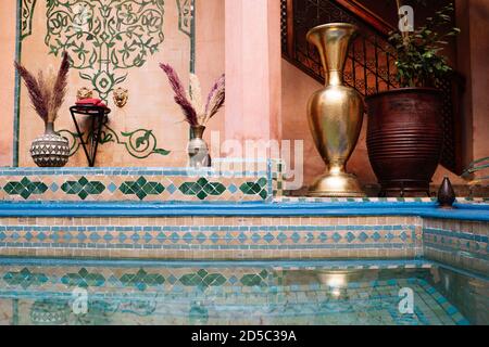 Cour intérieure avec carreaux colorés et une petite piscine décorée Avec une carafe dorée et des plantes au Maroc Banque D'Images