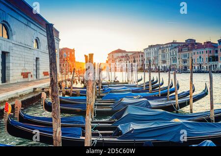 Gondoles amarrées sur l'embarcadère de la voie navigable du Grand Canal à Venise. Bâtiments de style baroque le long du canal Grande. Vue contre le soleil. Paysage urbain incroyable de Venise au coucher du soleil. Vénétie, Italie Banque D'Images