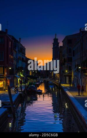 Paysage urbain de Venise avec canal d'eau étroit, remblai de fondamenta. Silhouette de pont, clocher et bâtiments. Vénétie, Nord de l'Italie. Vue vénitienne typique au coucher du soleil, vue verticale Banque D'Images