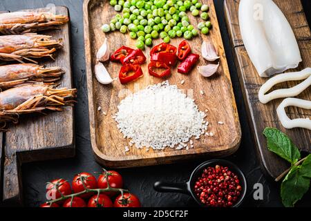 Ingrédients frais de paella non cuits avec crevettes géantes, moules et calmars sur fond noir texturé Banque D'Images