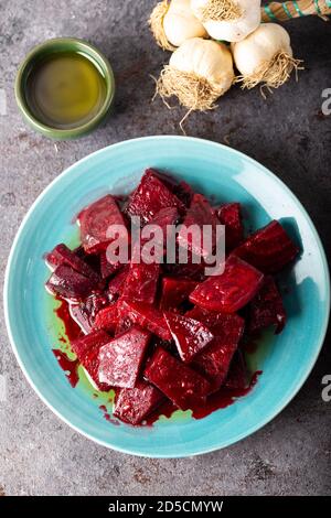 Salade de betteraves à l'ail et sauce à l'huile d'olive dans un plat sur fond sombre. Banque D'Images