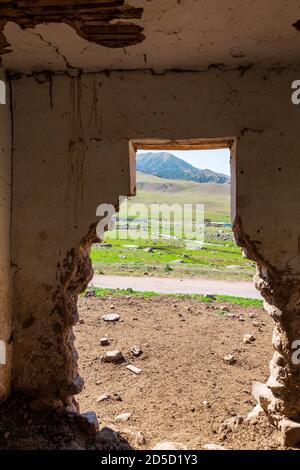 Une ancienne maison abandonnée. Les montagnes sont visibles par l'ouverture détruite. Le bâtiment est en adobe et en bois. Maison dans les montagnes de Kirghizs Banque D'Images