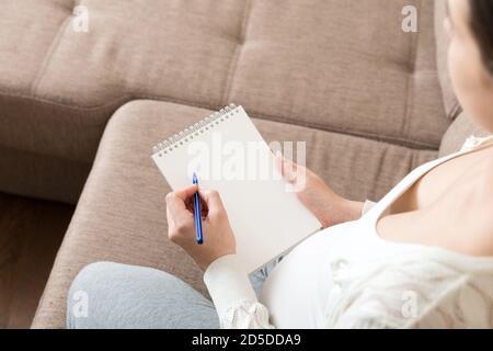 La femme enceinte prend des notes. Concept de grossesse, soins de santé, médecine. Mère attendant de bébé à la maison. Banque D'Images