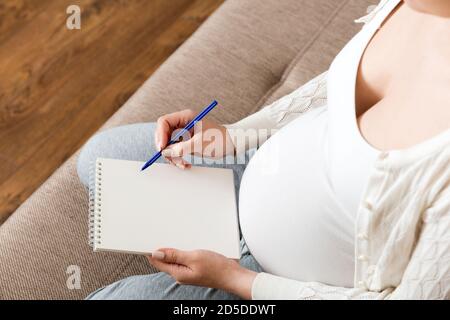 La femme enceinte prend des notes. Concept de grossesse, soins de santé, médecine. Mère attendant de bébé à la maison. Banque D'Images