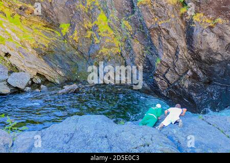 Deux gars regardent la chute d'eau de Rjukeukdefossen et la rivière d'une manière dangereuse, Hemsedal, Norvège. Banque D'Images