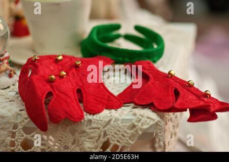 Carte du nouvel an avec fond flou de bokeh lumineux. Vue rapprochée d'un bord rouge-vert. oreilles de cerf avec cloches sur une nappe vintage. Noël Banque D'Images