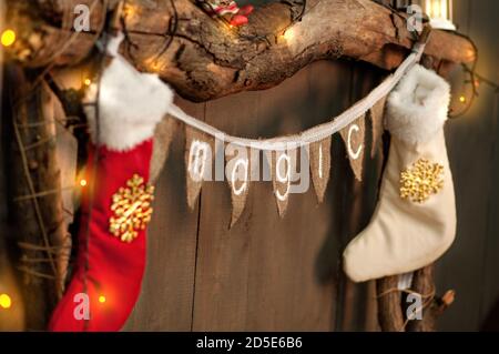 Sur une cheminée en bois faite de vieux rondins, il y a une bande de drapeaux avec l'inscription Magic, chaussettes blanc-rouge pour les cadeaux du Père Noël pendent sur le Banque D'Images