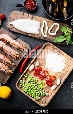 Ingrédients frais de paella non cuits avec crevettes géantes, moules et calmars sur fond noir texturé, vue du dessus Banque D'Images