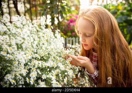 Floraison et brillance. Bonne petite fille caucasienne avec des fleurs dans un jardin à l'extérieur. Amour, famille, style de vie, récolte, concept d'automne. Gai, sain et charmant. Alimentation biologique, agriculture, jardinage. Banque D'Images