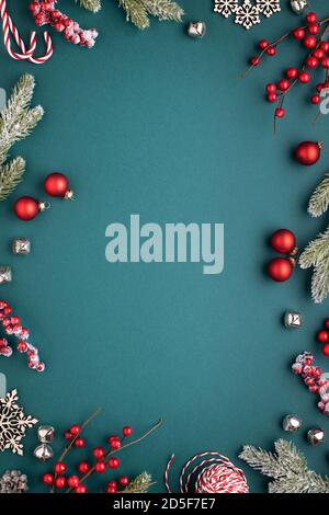 Cadre de Noël avec décorations classiques. Branches de sapin, boules rouges, cloches de jingle sur fond turquoise. Banque D'Images