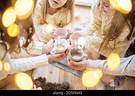 La veille de Noël, une famille boit du cacao. Carte de vacances du nouvel an. Gros plan de quatre tasses avec chocolat chaud, guimauves, hommes de pain d'épice. Flou bokeh Banque D'Images