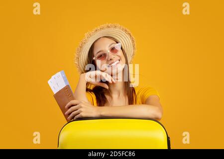 Femme élégante avec passeport et billets d'avion penchée sur une valise Banque D'Images