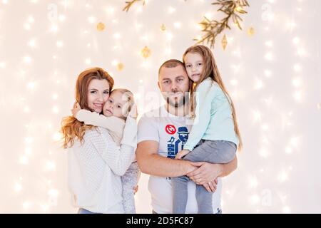 La famille heureuse s'amuse, se berner sur le fond des guirlandes jaunes de lumières et des branches d'arbre de Noël bokeh. Bon esprit du nouvel an. Parents Banque D'Images