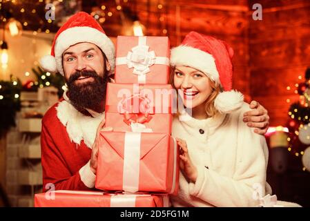 Couple amoureux profiter des fêtes de noël. Noël est l'heure de donner. Tant de boîtes pour nous. Cadeaux de noël préparés par la famille. Couple aimant déballage cadeaux avec arrière-plan arbre de noël. Banque D'Images