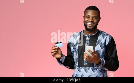 Homme africain joyeux avec smartphone montrant la carte de crédit Banque D'Images