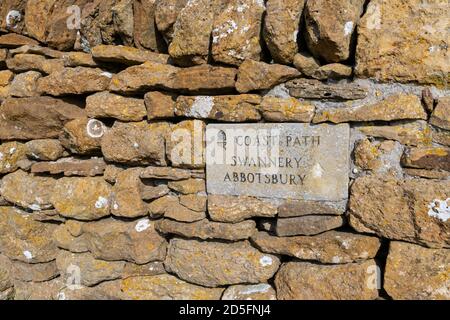 Marqueur de chemin de pierre pointant vers la Swannery d'Abbotsbury, installé dans un mur de pierre sèche sur le sentier de la côte sud-ouest sur la côte du patrimoine, à Abbotsbury, Dorset Banque D'Images