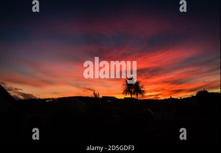 Un ciel rouge d'hiver tandis que le soleil se couche sur le village de Budleigh à Devon. Banque D'Images