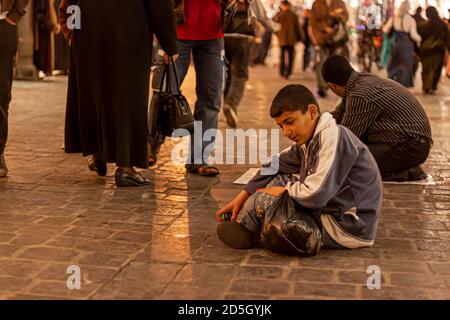 Damas, Syrie 03/28/2010: Un garçon arabe est assis sur le sol du souq Al hamidiyah (un marché couvert bondé) essayant de vendre de petits jouets pour gagner un Banque D'Images