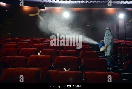 New Delhi, Inde. 13 octobre 2020. Un travailleur portant un équipement de protection individuelle (EPI) assainit les sièges d'une salle de cinéma à New Delhi, en Inde, le 13 octobre 2020. Credit: STR/Xinhua/Alay Live News Banque D'Images