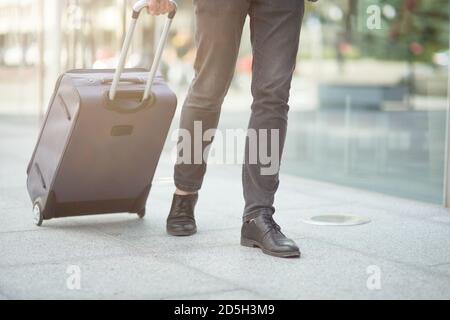 Photo courte d'un homme d'affaires tirant sa valise à l'extérieur du aéroport Banque D'Images