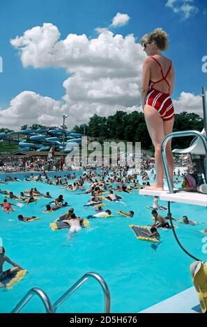 Les supports de sauveteurs féminins surveillent la foule des nageurs dans un piscine publique Banque D'Images