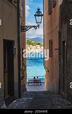 Couple de jeunes assis sur un banc face à la mer, Bogliasco, Ligurie, Italie Banque D'Images