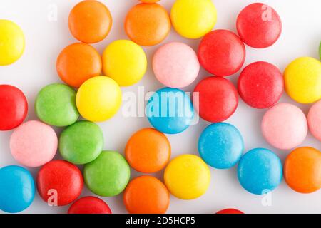 Dragées en chocolat multicolores colorées sur fond blanc. Vue de dessus, gros plan. Banque D'Images