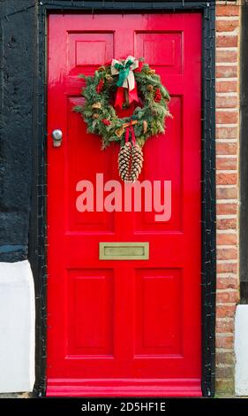 WINSLOW, Royaume-Uni - 29 décembre 2019. Porte avant rouge de la maison du Royaume-Uni à Noël avec un ornement de couronne de Noël Banque D'Images