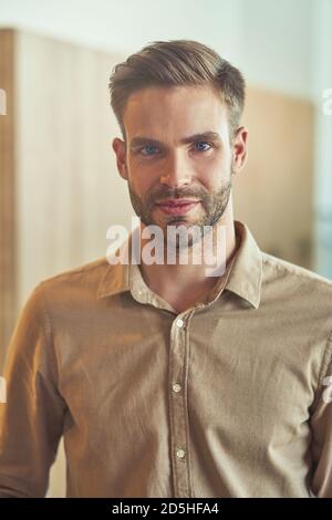 Photo verticale d'un jeune homme d'affaires élégant en tenue classique regarder la caméra tout en posant dans le bureau moderne Banque D'Images