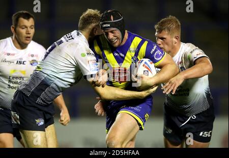 Le Chris Hill (au centre) de Warrington Wolves est abordé par James Harrison (à gauche) de Leeds Rhinos et Tom Holroyd lors du match de la Super League de Betfred au stade Halliwell Jones, à Warrington. Banque D'Images