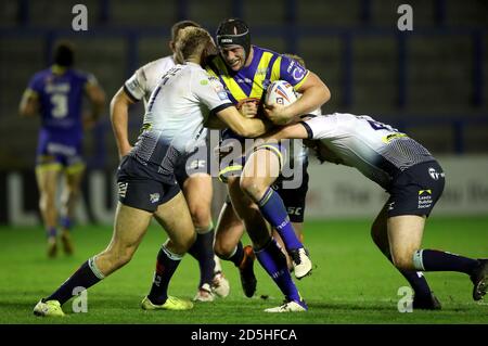 Le Chris Hill (au centre) de Warrington Wolves est abordé par James Harrison (à gauche) de Leeds Rhinos et Loui McConnell lors du match de la Super League de Betfred au stade Halliwell Jones, à Warrington. Banque D'Images