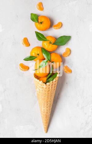 Fruits mandarine orange ou mandarine au cornet de glace gaufrée avec des tranches sur fond de béton. Concept de la nourriture de Noël en hiver. Vue du dessus. flat Lay. ve Banque D'Images