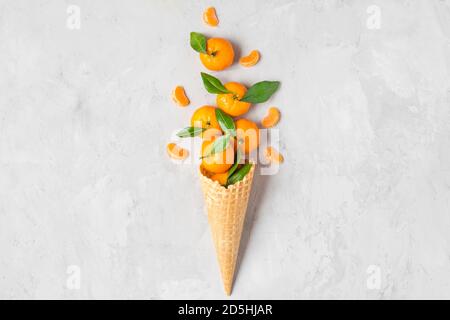 Mandarine ou orange mandarine dans un cône de glace gaufré avec des tranches de fruits sur fond de béton. Concept de la nourriture de Noël en hiver. Vue du dessus. flat Lay Banque D'Images