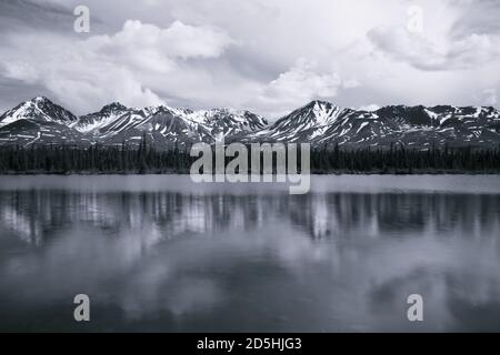 Sommets enneigés avec de la neige sur le sommet d'une rivière peu profonde au début de l'été. Banque D'Images