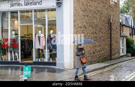 Londres, Grande-Bretagne. 13 octobre 2020. Une femme passe devant un magasin à Londres, en Grande-Bretagne, le 13 octobre 2020. Le taux de chômage britannique a grimpé à un niveau record de trois ans, à 4.5 pour cent de juin à août 2020, alors que le marché du travail du pays a continué d'être touché de manière significative par la pandémie COVID-19, qui devrait rendre plus de personnes sans emploi en hiver, a déclaré l'Office britannique des statistiques nationales (ONS) mardi. Credit: Han Yan/Xinhua/Alay Live News Banque D'Images