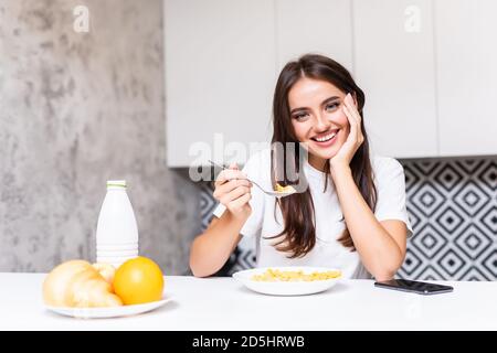 Gros plan de la jeune femme souriante mangeant des céréales de petit déjeuner de bol à la maison. Banque D'Images