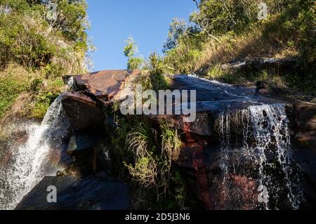 L'extrémité supérieure de la cascade de Mato Limpo entourée d'une végétation verte avec l'eau cristalline qui coule et éclabousse sur les rochers. Cascade localisée Banque D'Images
