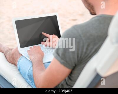 Concept de pigiste. Homme utilisant un ordinateur portable à écran tactile avec écran noir vierge. Banque D'Images