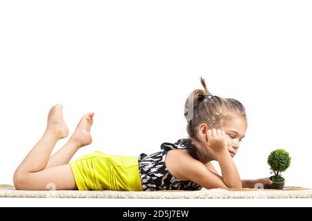 mignon litthe fille couché sur le sol et jouant avec petit petit arbre jouet Banque D'Images