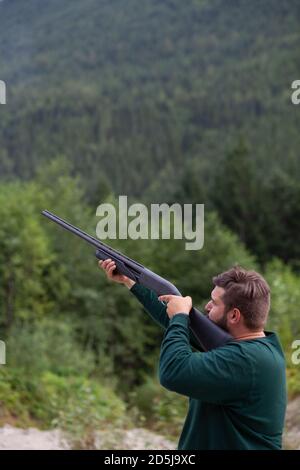 Un homme tient un fusil de chasse prêt à tirer sur un pigeon d'argile pour pratiquer son but à Squamish, en Colombie-Britannique Banque D'Images