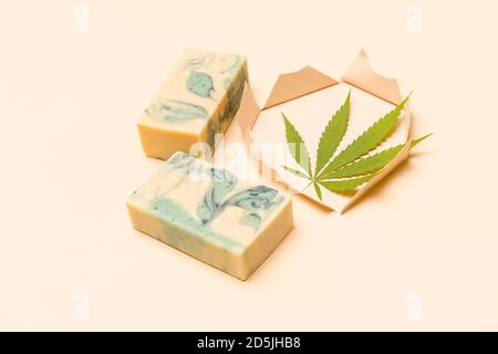 Savon de chanvre fait maison et feuille verte de marijuana dans le trou de papier coupé. Savon biologique spa. Produit de soin organique de la peau avec CBD médicinal. Concept zéro déchet Banque D'Images