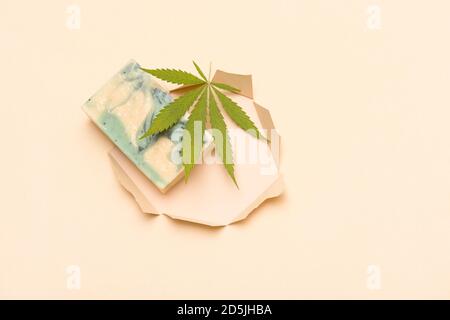 Savon de chanvre fait maison et feuille verte de marijuana dans le trou de papier coupé. Savon biologique spa. Produit de soin organique de la peau avec CBD médicinal. Concept zéro déchet Banque D'Images