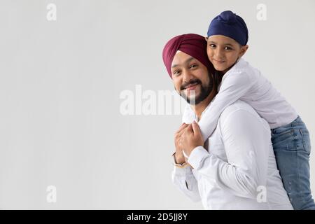 UN PÈRE ET UN FILS SIKH SE TENANT ENSEMBLE ET REGARDANT À L'APPAREIL PHOTO Banque D'Images