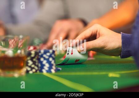 Gros plan de la main du joueur tenant une paire d'as pendant jouer au poker le soir du casino Banque D'Images