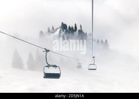 Remontée mécanique sur le fond des montagnes dans le brouillard. Magnifique luxe meilleur arrière-plan de vacances d'hiver. Banque D'Images