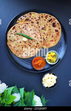 Aloo / Alu Paratha ou pain plat fourré de pommes de terre indiennes. Servi avec du beurre pour le petit déjeuner, des pommes de terre au cornichon et au masala, avec thé au masala et chai. Banque D'Images