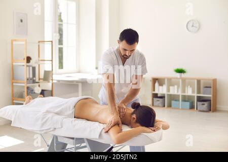 Femme allongée sur une table de massage recevant un massage du corps dans moderne clinique de santé ou centre de bien-être Banque D'Images
